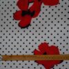 Tela flamenca blanca con lunares negros y flores rojas grandes estampadas, ideal para trajes de flamenca y confección sevillana.