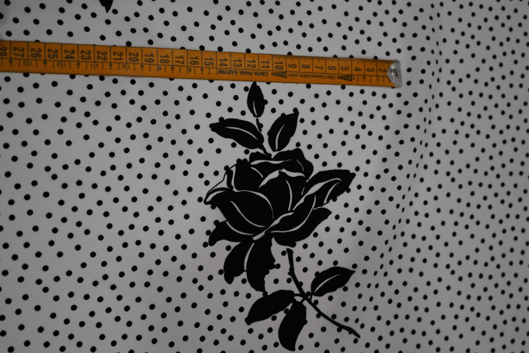 Tela flamenca blanca con pequeños lunares negros y siluetas de flores negras grandes estampadas, ideal para trajes de flamenca.