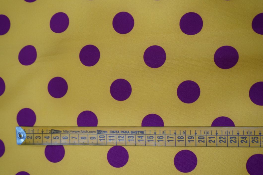 Tela flamenca amarilla con lunares morados medianos, ideal para trajes de flamenca.